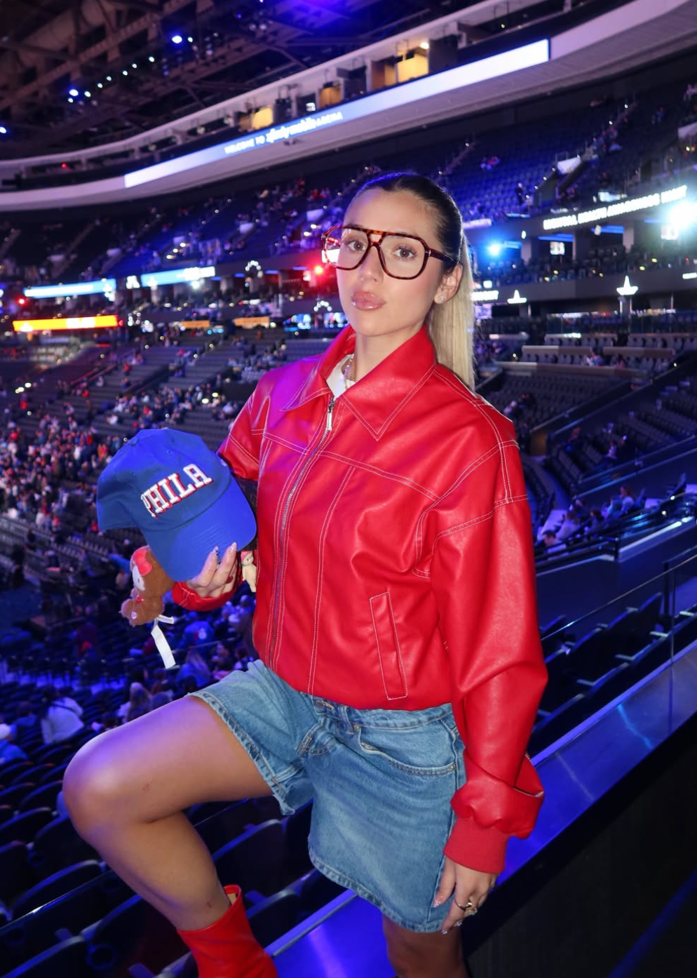 Jacklyn in red jacket, with glasses, at a sporting event